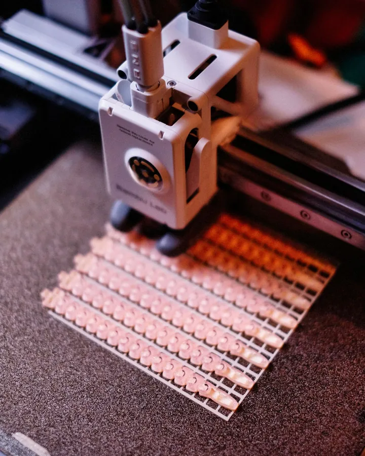 Cabezal de una impresora 3D formando una retícula de piezas pequeñas